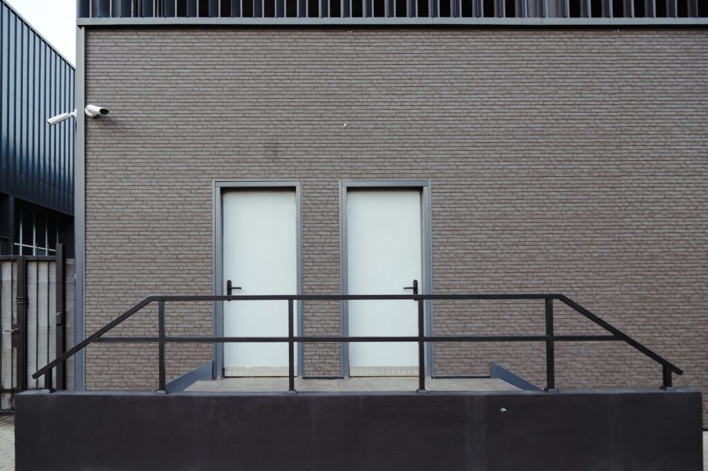 Modern industrial facade with emergency exit doors and stairs, cctv, minimal straight shape building